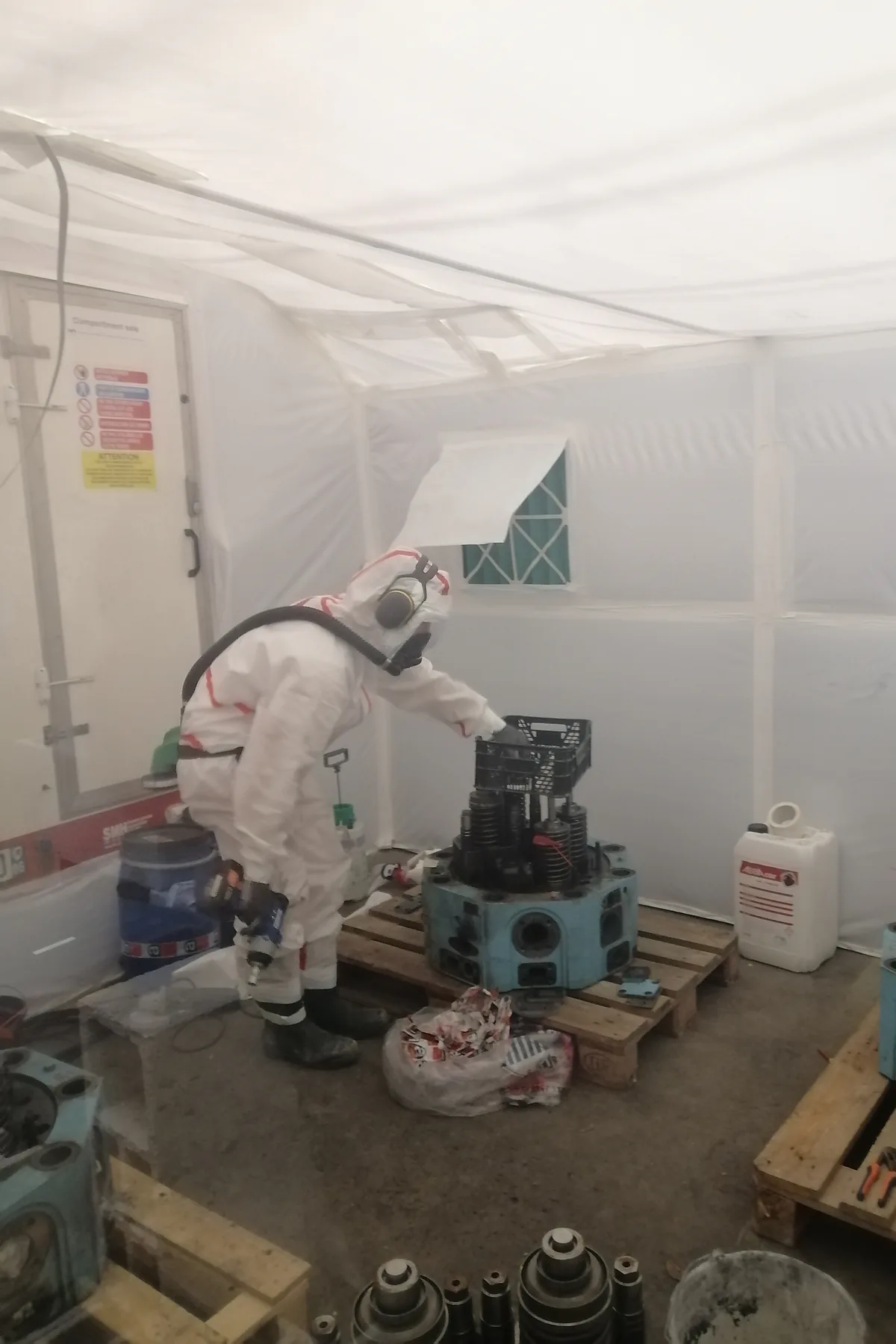 Opérateur en combinaison intégrale et masque à adduction d'air au travail dans une zone confinée